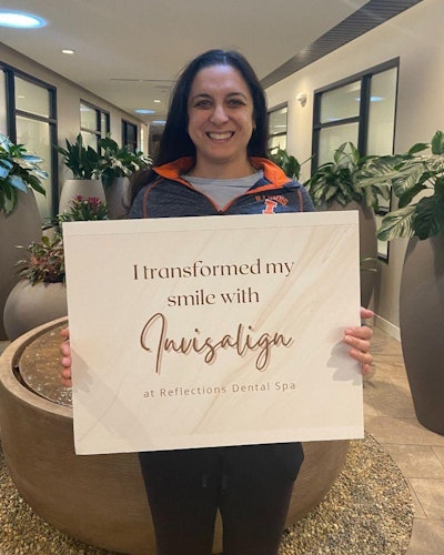 Patient testimonial holding a sign which reads their smile was transformed with invisalign
