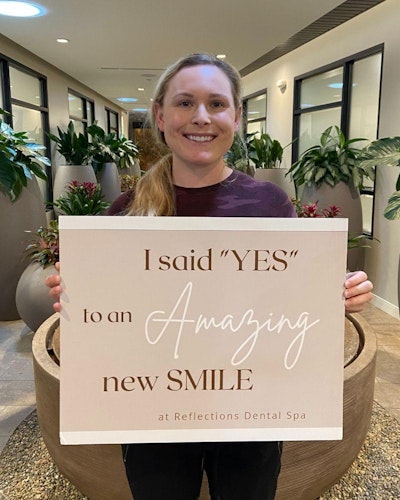 Patient testimonial holding a sign which reads their smile was transformed at Reflections Dental Spa
